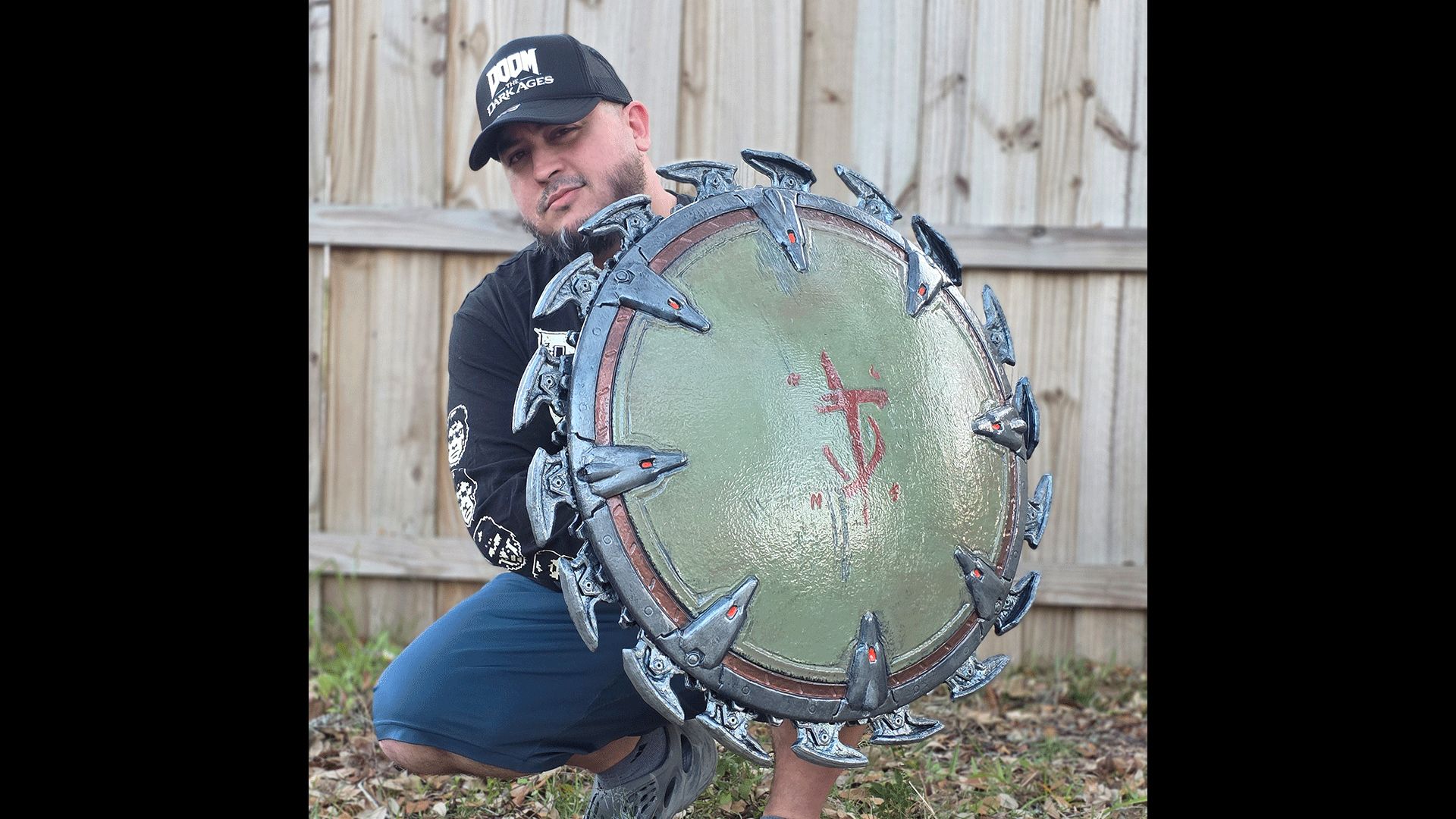 Artist GameQraft crouches behind his fabricated Shield Saw